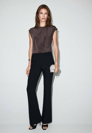 Brown short-sleeve top paired with black flared trousers. Accessorized with a metallic mesh clutch and black open-toe heels. Simple design.