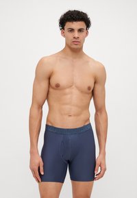 Marineblå boxershorts med tettsittende passform, myk stoff og en midjebånd med "YOUR UNDER" tekst. Inkluderer detalj med åpning foran.
