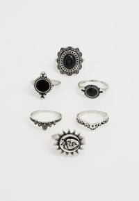 Sex silverringar med svarta stenar. Designerna inkluderar utsmyckade mönster, släta ytor och ett solmotiv. Olika former och storlekar finns.