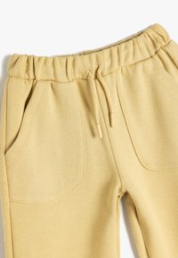 Gule bomuldsjoggingbukser med elastisk talje med snoretræk, to for- og en baglomme samt et struktureret, vævet stofdesign.