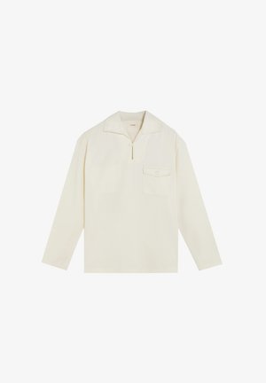 Jersey de manga larga color crema con cuello pequeño, cremallera hasta la mitad y bolsillo en el pecho con botón, mostrado sobre un fondo blanco.