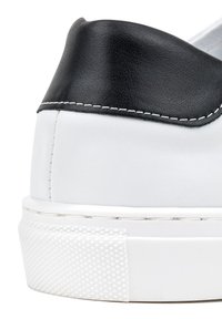 Białe sneakersy z czarną skórzaną nasadką na pięcie. Teksturowana powierzchnia, biała gumowa podeszwa z diamentowym wzorem oraz kontrastowe przeszycia.