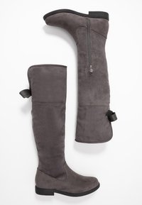 Šedé kozačky nad kolena z jemného semiše s plochou podrážkou. Mají boční zip a poutko na vrcholu pro snadné obouvání.