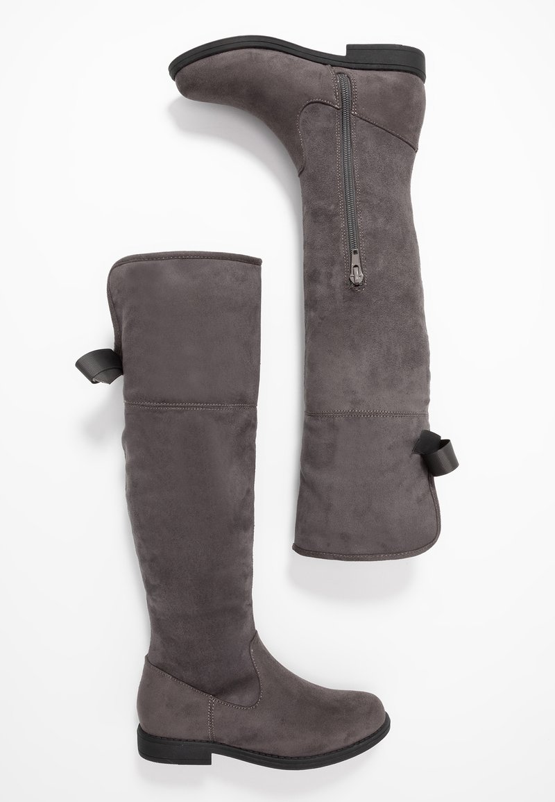 Šedé kozačky nad kolena z jemného semiše s plochou podrážkou. Mají boční zip a poutko na vrcholu pro snadné obouvání.