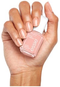 Vernis à ongles Essie dans une teinte rose douce, contenu dans un flacon transparent avec un capuchon blanc. Les ongles sont brillants et soigneusement manucurés.