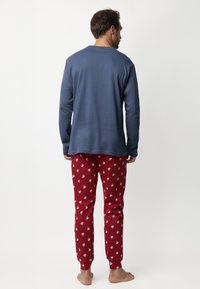 Conjunto de ropa de estar en casa para hombres que incluye una camisa de manga larga azul y pantalones de pijama rojos con un patrón de pequeñas figuras blancas. Mezcla de algodón, corte relajado.
