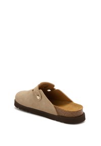 Beige mockasinsandaler i mocka med justerbar rem, vadderad korksula och mörk gummisula, vinklad för att visa sidan och baksidan.