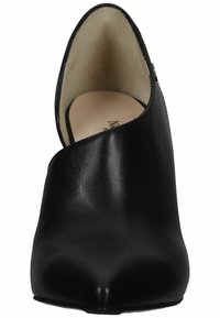 Scarpa nera in pelle con tacco e punta appuntita. Presenta un design con ritaglio curvo. Texture liscia con finitura opaca.