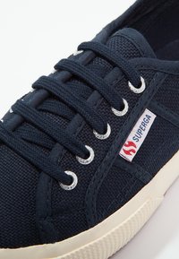 Marine lerret sneakers med metallhull og hvite snørebånd. Har en teksturert overflate og en kontrastfylt kremfarget gummisål, med et logomerke.