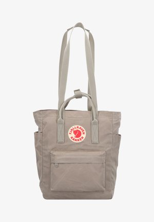 Gray canvas tote bag with two top handles and long shoulder straps, featuring a front pocket and a circular logo patch.