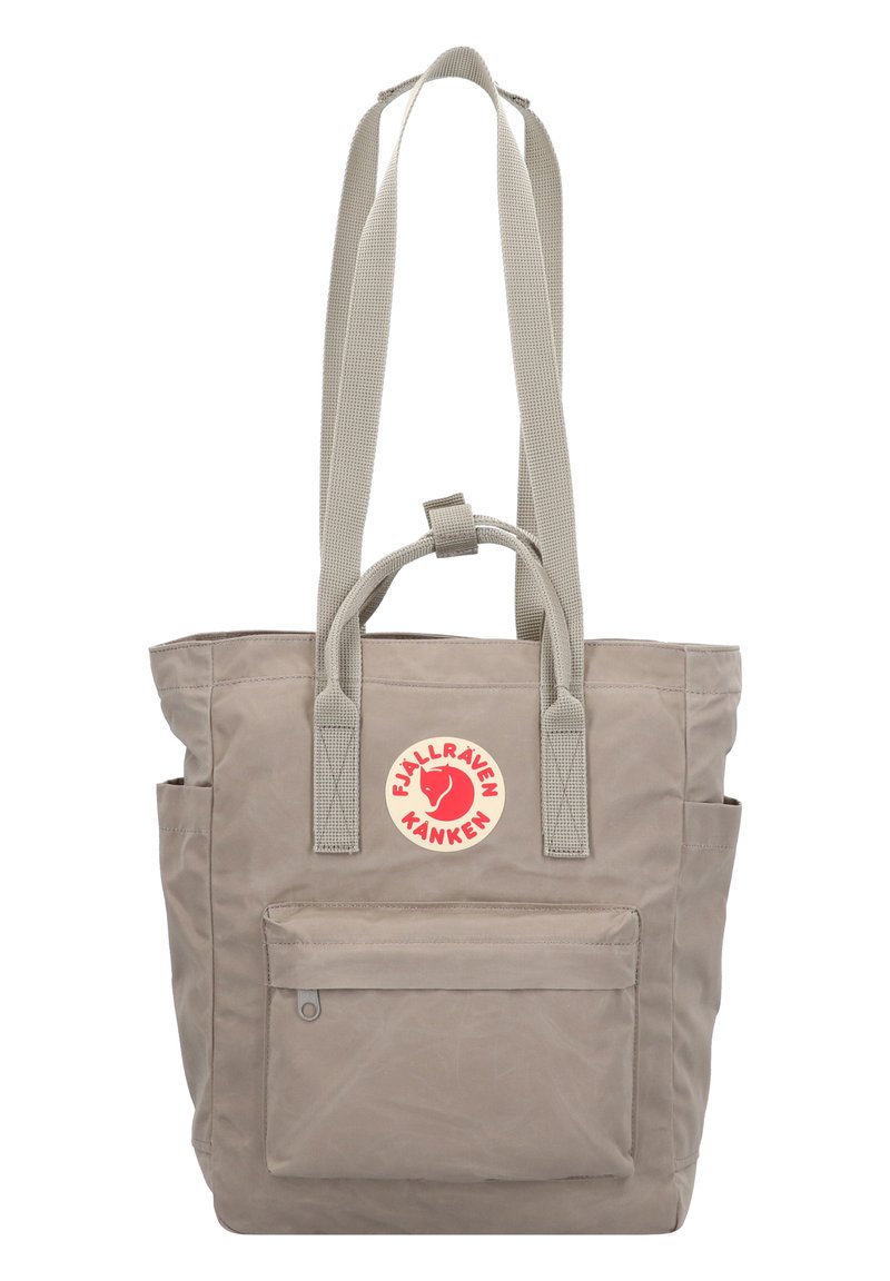 Grijze canvas draagtas met twee handvatten aan de bovenkant en lange schouderbanden, met een voorvak en een ronde logopatch.