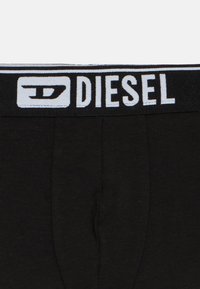 Μαύρα ανδρικά εσώρουχα τύπου boxer με μαλακή ελαστική μέση, όπου αναγράφεται με λευκά γράμματα το όνομα της μάρκας «DIESEL». Ομαλή υφή υφάσματος.