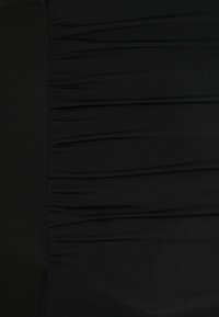Zwarte zwemkledingstof met een geplooide textuur, met horizontale plooien en een glad oppervlak. Rekbaar materiaal zorgt voor een comfortabele pasvorm.
