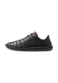Black leather sneaker with a textured finish, low-top design, multiple lateral elastic bands, and a rubber sole. Red branding accent near the heel.