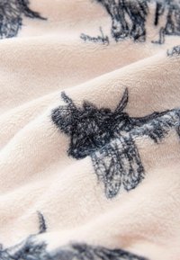 Puha bézs szövet fekete részletes tehénvázlatokkal, nyomtatva egy texturált, bolyhos felületen.