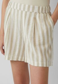 Leinen-Shorts mit einem gestreiften Muster in Beige und Creme, ausgestattet mit einem elastischen Bund und seitlichen Taschen sowie gefältelten Designdetails.