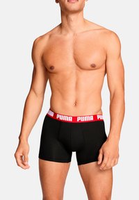 Schwarze Baumwoll-Boxershorts mit rotem Bund und weißem "PUMA"-Logo. Eng anliegendes Design mit flachen Nähten für eine glatte Textur.
