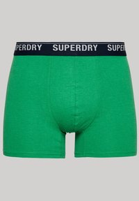 Groene katoenen boxershorts met een zwarte tailleband waarop "SUPERDRY" in witte letters staat. Het design is slim fit met een gladde textuur.