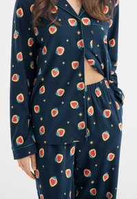 Granatowy zestaw piżamowy z wzorem serc i gwiazd w kolorach czerwonym, żółtym i niebieskim; bluzka z długim rękawem z zapięciem na guziki oraz pasujące spodnie na gumce.