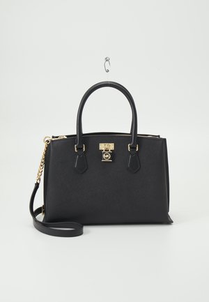 Sac à main en cuir noir avec double poignée, bandoulière chaîne dorée et détail cadenas doré avec logo MK, sur fond blanc.