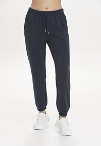 Marineblaue Sweatpants aus weicher Baumwolle mit einem Kordelzugbund, seitlichen Taschen und elastischen Bündchen an den Knöcheln.