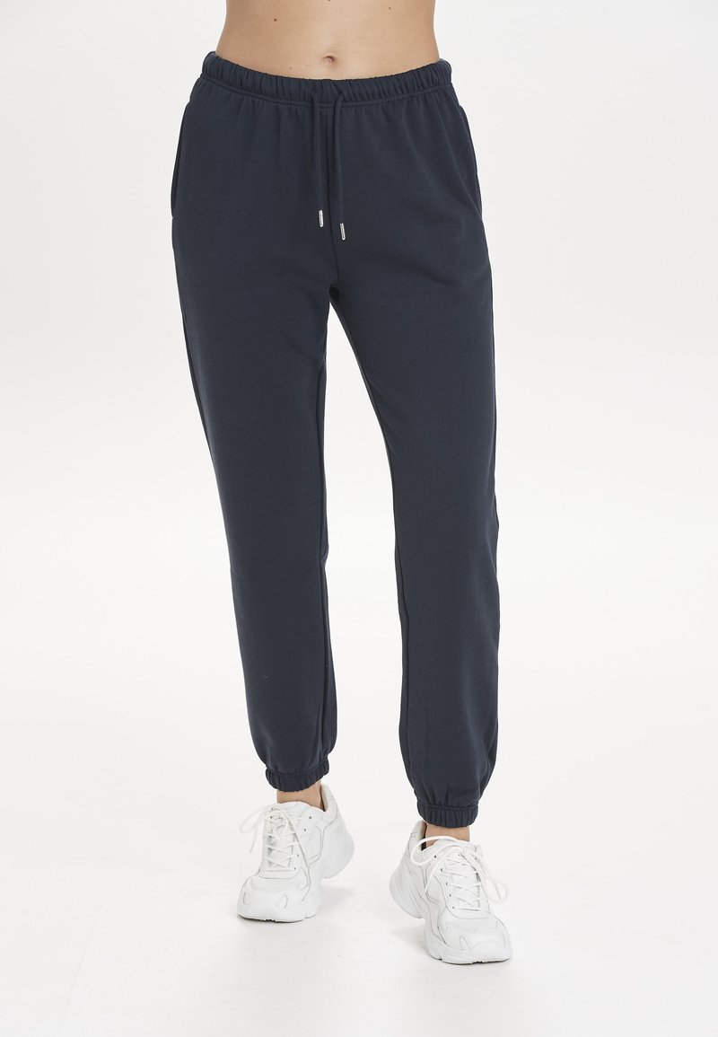Marineblaue Sweatpants aus weicher Baumwolle mit einem Kordelzugbund, seitlichen Taschen und elastischen Bündchen an den Knöcheln.