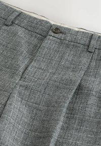 Hnedé nohavice so šedým vzorom vyrobené z tkaného materiálu, s námestníkovým designom, zapínaním na gombík a viditeľnými pútkami na opasok.
