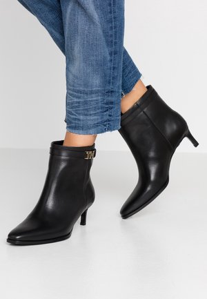 Sorte læderankelstøvler med spids tå og en slank hæl. Har en dekorativ gulddetalje på skaftet. Båret med blå denim.