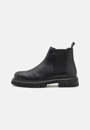 Stivali Chelsea in pelle nera con pannelli elastici laterali, punte arrotondate e suole in gomma rigata. Presenta un tirante sul retro.