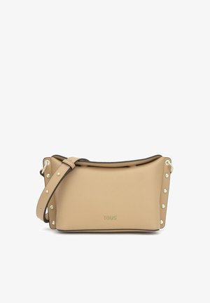 Beżowa skórzana torba na ramię z regulowanym paskiem i złotymi ćwiekami po bokach, małe wytłoczone logo "TOUS" na środku z przodu.