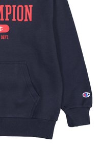 Felpa blu navy con tasca frontale, polsini e orlo a coste. Logo "Champion" in rosso sul petto con toppa del logo sulla manica.