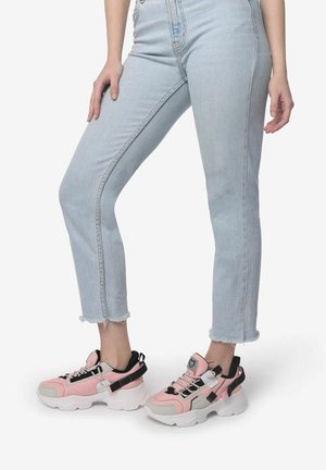 Roze en grijze chunky sneakers met een dikke witte zool, voorzien van zwarte accenten en een gewatteerde kraag, gecombineerd met lichtgewassen cropped jeans.