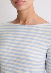 Licht katoenen top met horizontale blauwe en beige strepen, een brede halslijn en een ontspannen pasvorm met een gladde textuur.