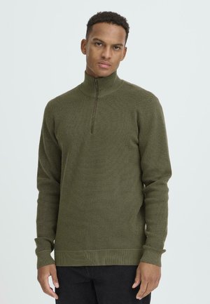 Olivgrüner Strickpullover mit hohem Kragen und Viertelreißverschluss, ausgestattet mit gerippten Bündchen und Saum für eine taillierte Optik.