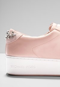 Sneaker in pelle rosa con suola bianca spessa e dettaglio di fiore con strass sul tallone, logo Michael Kors impresso sulla suola.