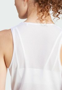 Witte mouwloze sporttop met een gaasontwerp, voorzien van kleine gaatjes voor ademend vermogen en een gladde stof textuur.