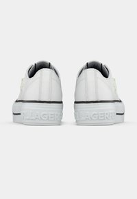 Ζευγάρι λευκές sneakers χαμηλού τύπου με χοντρές σόλες, μαύρο περίγραμμα και ανάγλυφο λογότυπο «KARL LAGERFELD» στη φτέρνα.