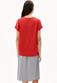 Rode t-shirt met korte mouwen van zacht katoen, gecombineerd met een grijs, knielang rokje met een simpel ontwerp en een relaxte pasvorm.