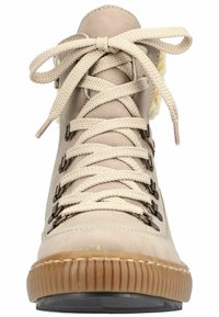 Bottine beige à lacets en daim, avec des œillets en métal, une semelle en caoutchouc texturée et un intérieur doux et pelucheux autour du col.