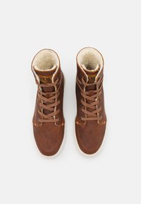 Brown leather high-top shoes with white rubber soles and laces. Interior features a soft, cream lining. Logo visible on the tongue.