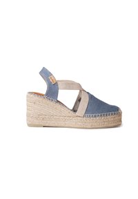 Alpargatas con cuña de denim, con tiras cruzadas de tela beige, suela de yute trenzado y una pequeña etiqueta de logo en el talón. Colores azul oscuro y beige claro.