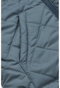 Gepolsterte Jacke aus dunkelblauem Stoff mit glatter Textur, diagonalen Nähten und einer Reißverschlusstasche mit kontrastierendem marineblauen Reißverschluss.