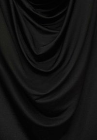Tela negra drapeada con textura suave, que presenta pliegues profundos y una superficie lisa, resaltando su diseño flexible y fluido.