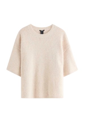 Lyhythihainen neule vaaleanbeigessä, valmistettu pehmeästä kankaasta. Siinä on resoroitu pääntie ja väljä istuvuus sekä teksturoitu, hieman pörröinen pinta.