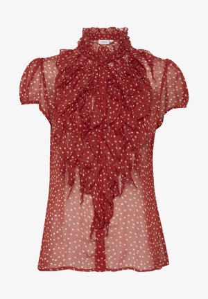 Piros, áttetsző blúz pöttyös mintával. Magas fodros gallérral rendelkezik, és réteges fodros részletezéssel az elején. Rövid ujjú.