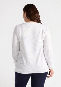 Felpa bianca con un motivo floreale lilla, colletto rotondo e maniche lunghe, con una vestibilità rilassata e spacco laterale all'orlo.