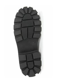 Suela de bota de goma negra con surcos profundos y una superficie texturada. Presenta una forma redondeada con perfiles angulares en el diseño de la suela.