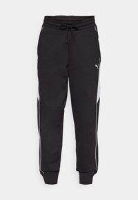 Sweatpants pretos com um cós elástico e cordão, apresentando riscas laterais brancas e um design de perna afunilada. O material parece macio.