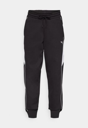 Svarte joggebukser med elastisk midje og snor, med hvite sidestreker og en smalere ben-design. Materialet ser mykt ut.