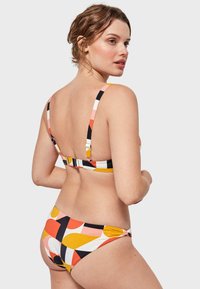 Conjunto de bikini con un patrón geométrico multicolor, con tirantes ajustables y un cierre en la parte posterior. Fabricado en tela suave y elástica.